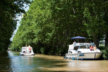 Canal du Midi. Bateaux amarrés ou en navigation à l'ombre des arbres.