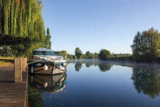 Charenta - Francia - Barco sin licencia de Nicols amarrado a un pontón de madera fijo en el Halte de Chaniers en el Charente